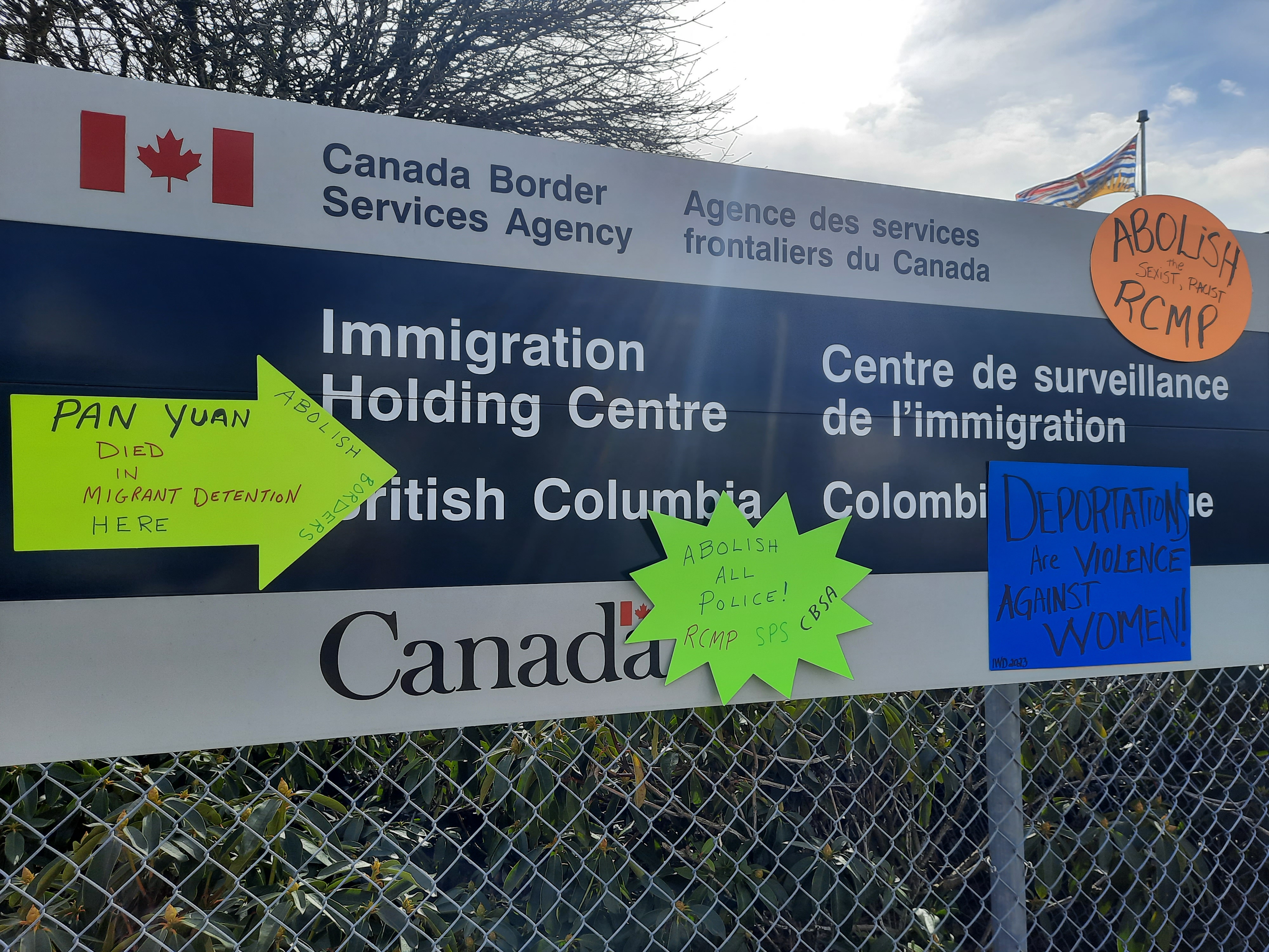 a sign towards an immigration holding centre covered with notes about abolition 