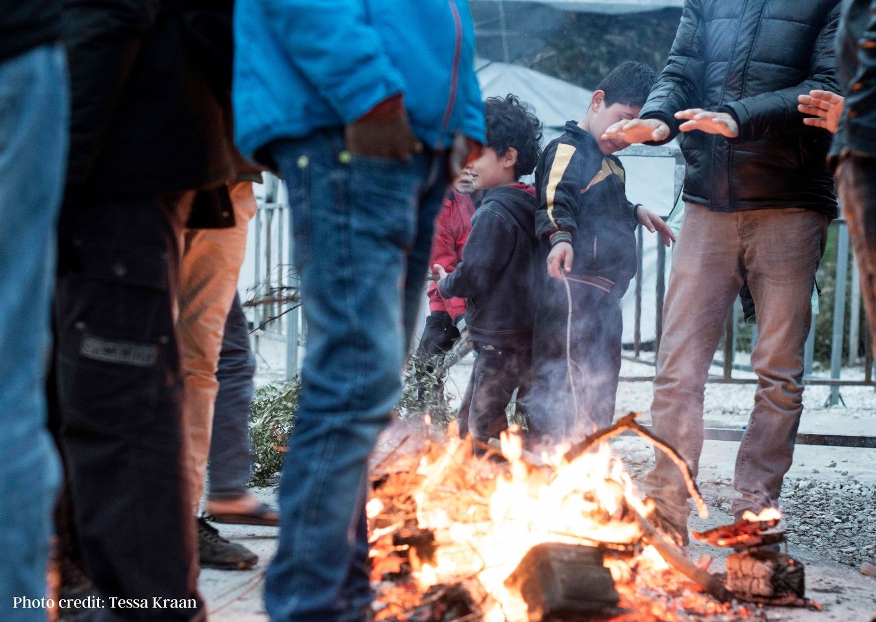 Men and children around a fire to warm up