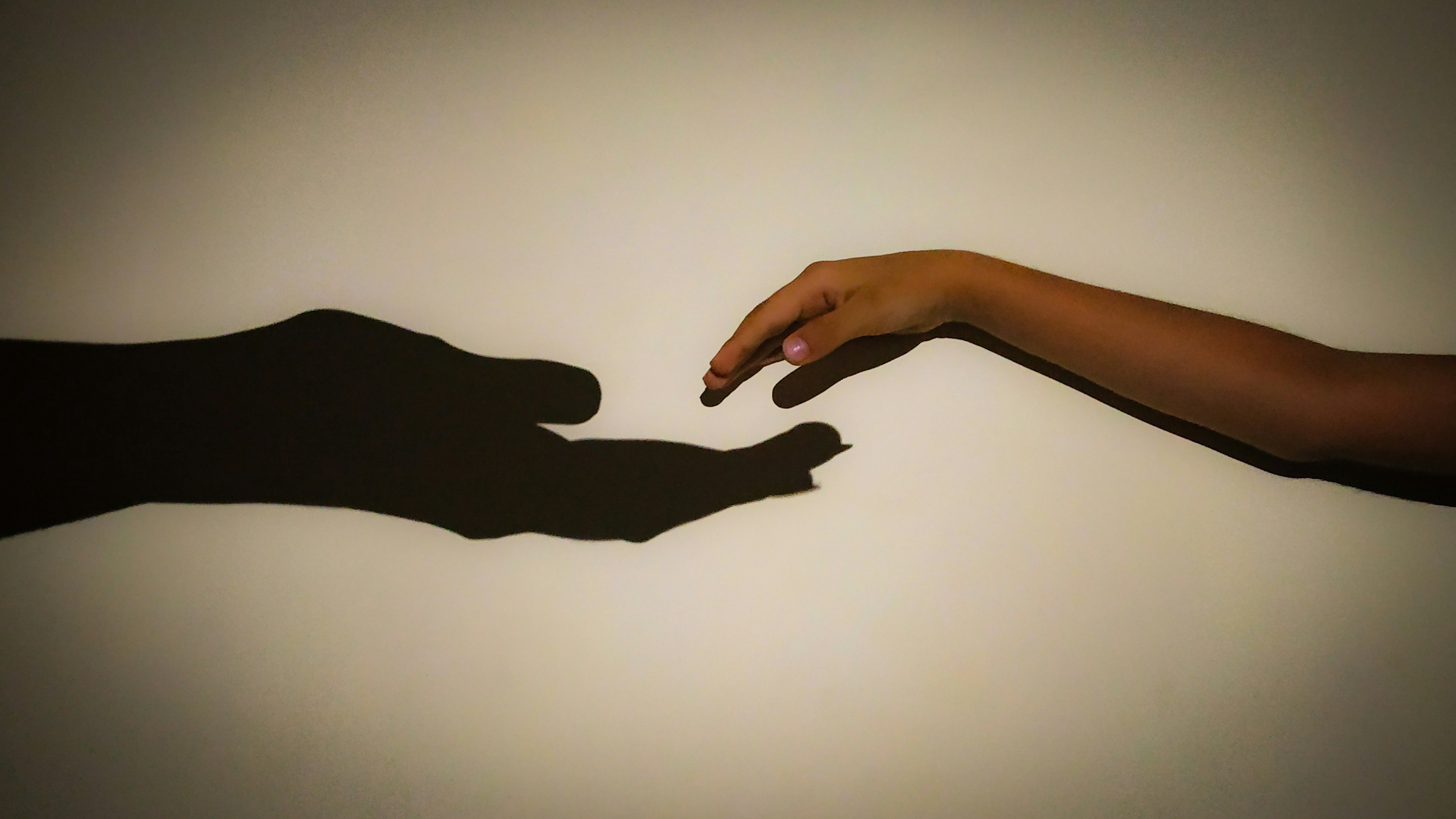 photo of a child's hand reaching for a shadow of a much bigger hand 