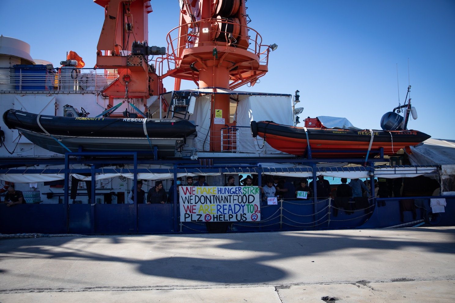 People protesting holding signs on a rescue ship