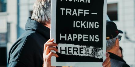 Man holding a sign that says "human trafficking happens here"