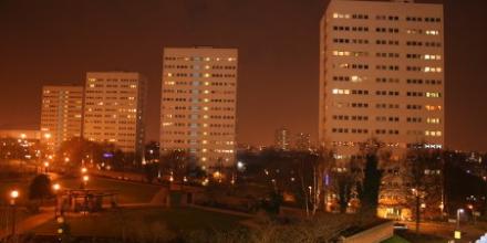 This image shows several high rise building blocks against a red gloomy nightsky. 