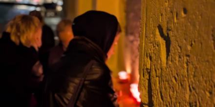 An activist lights a candle at the 2025 CommemorAction in Malta.