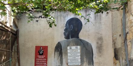 photo of a wall with a mural depicting a man from behind, next to a red sign that says "zone interdite"