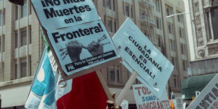 Picture of a sign that says "No Mas Muertes en la Frontera" and one that says "La Ciudadania es esencial!"
