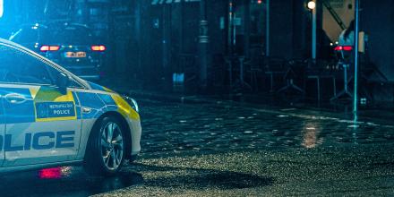 Partial view of a police car on a dark road.