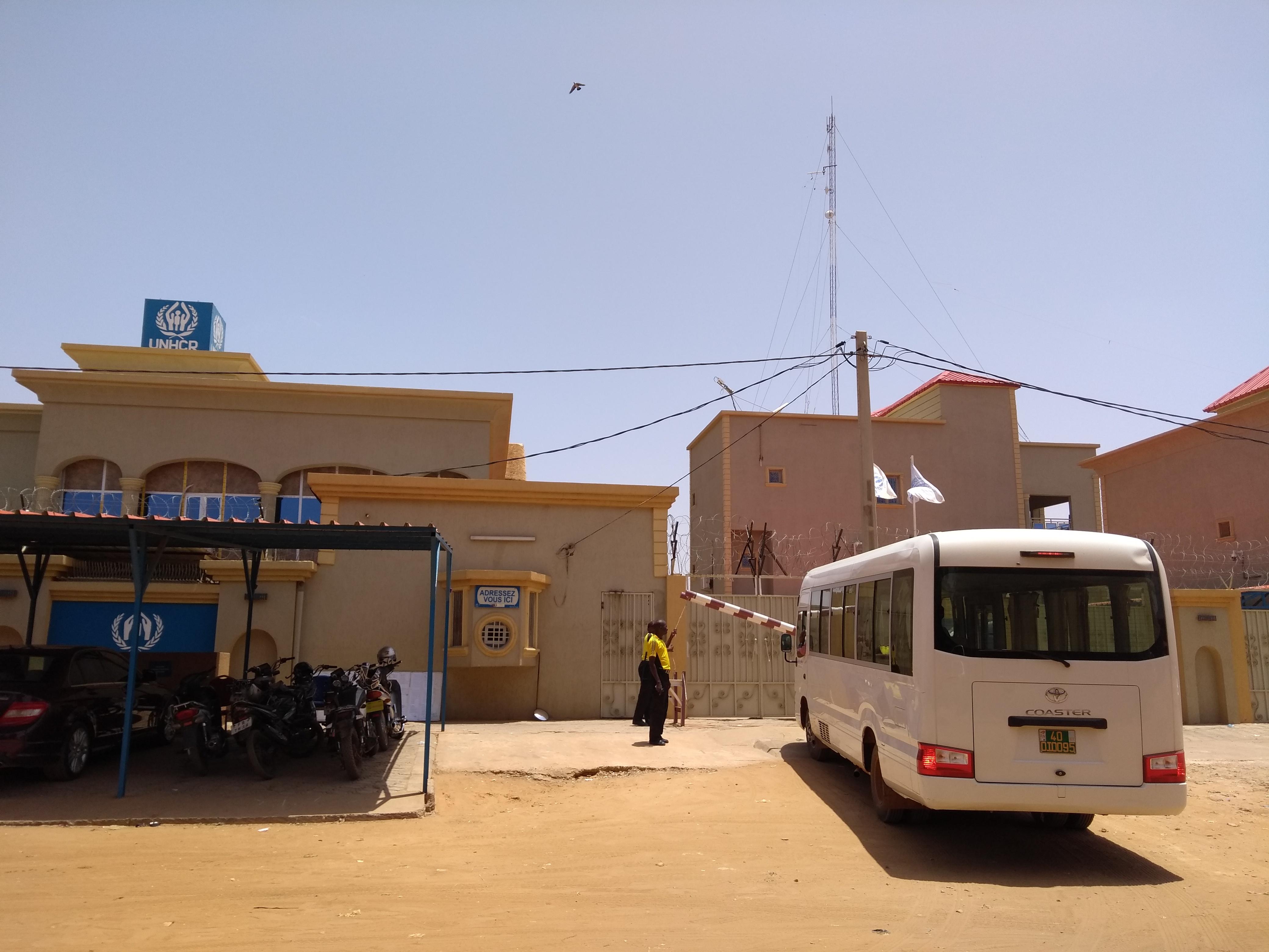 photo outside UNHCR office in Niger, showing the logo and a white bus with a person looking to the right side