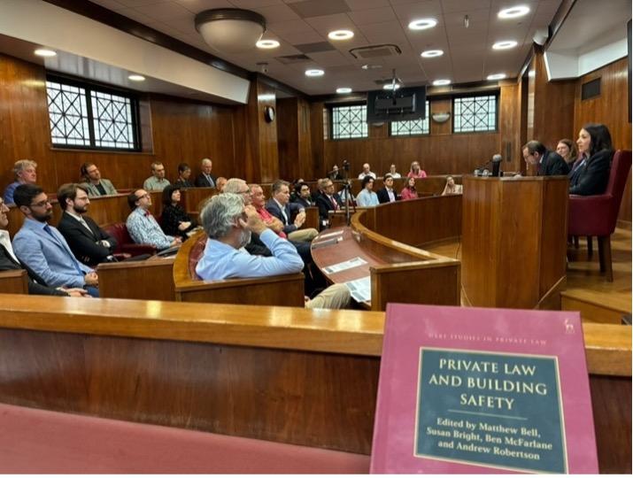 An image showing a busy conference room with academic having a discussion, with an edition of Sue Bright and Matthew Bell's forthcoming book in the bottom left corner.