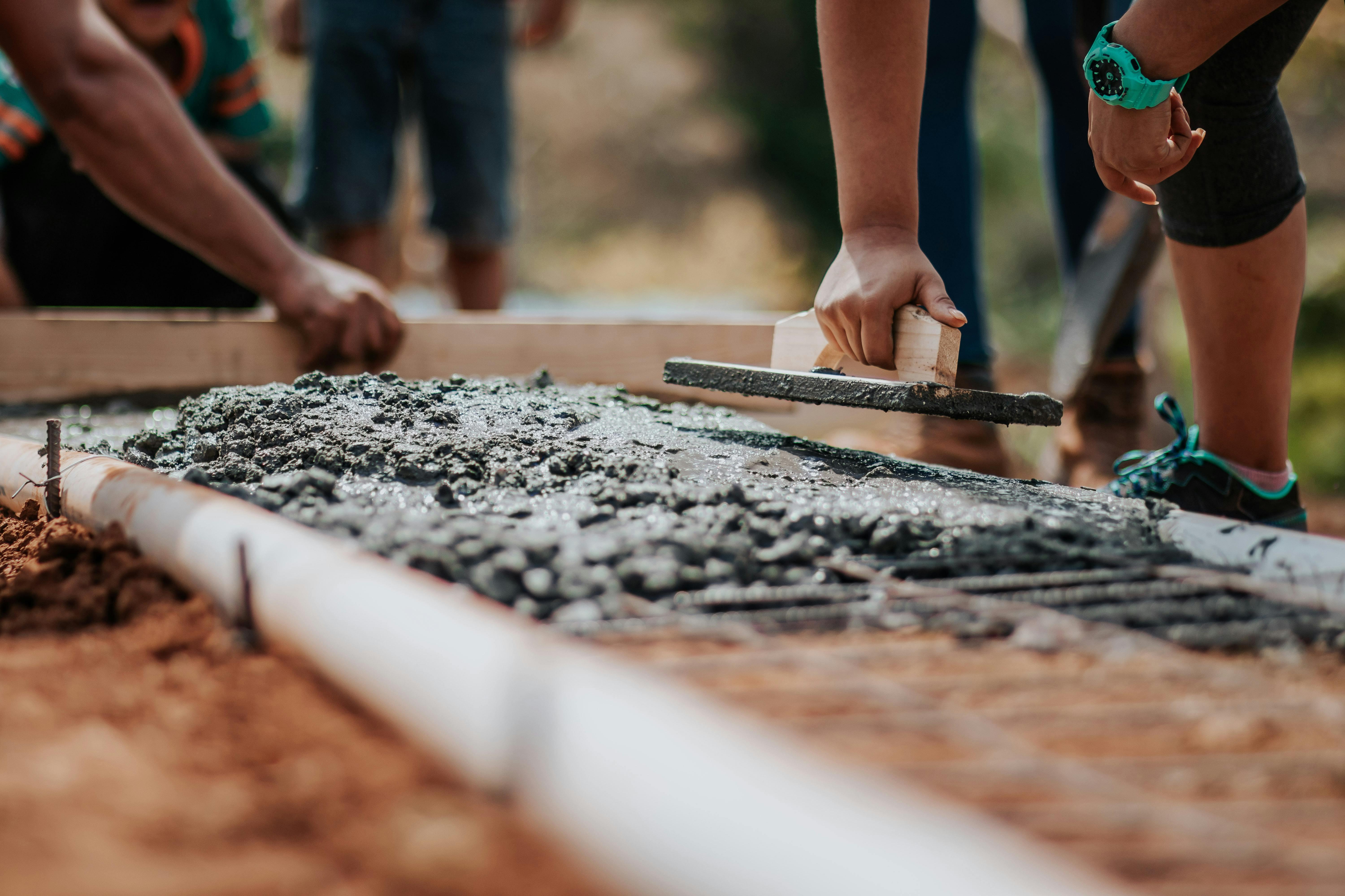 A selective focus image showing the laying of cement on a building site.