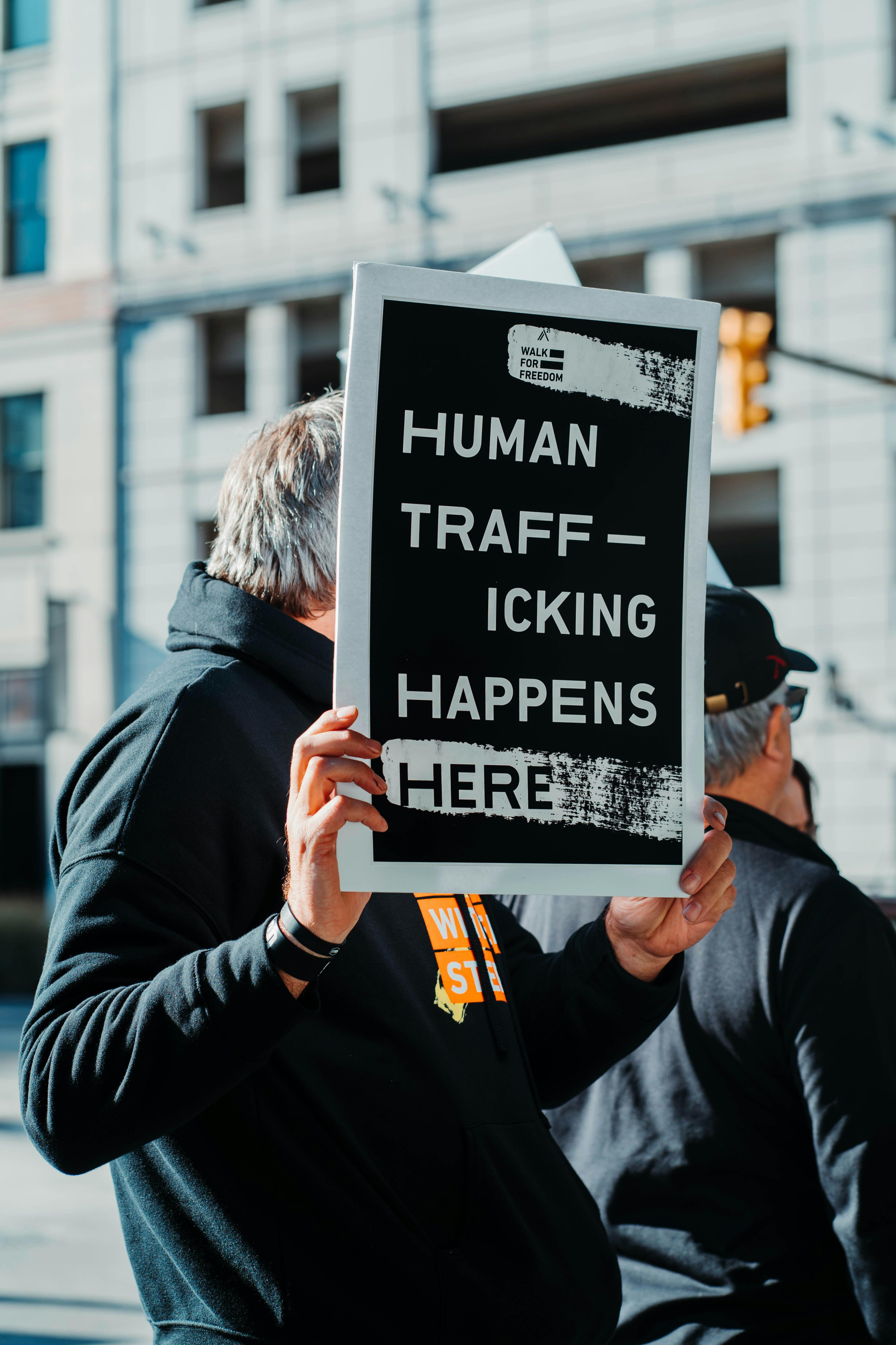 Man holding a sign that says "human trafficking happens here"