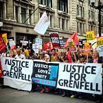 A busy protest showing several signs demanding justice for Grenfell, criticising austerity and the conservative government.
