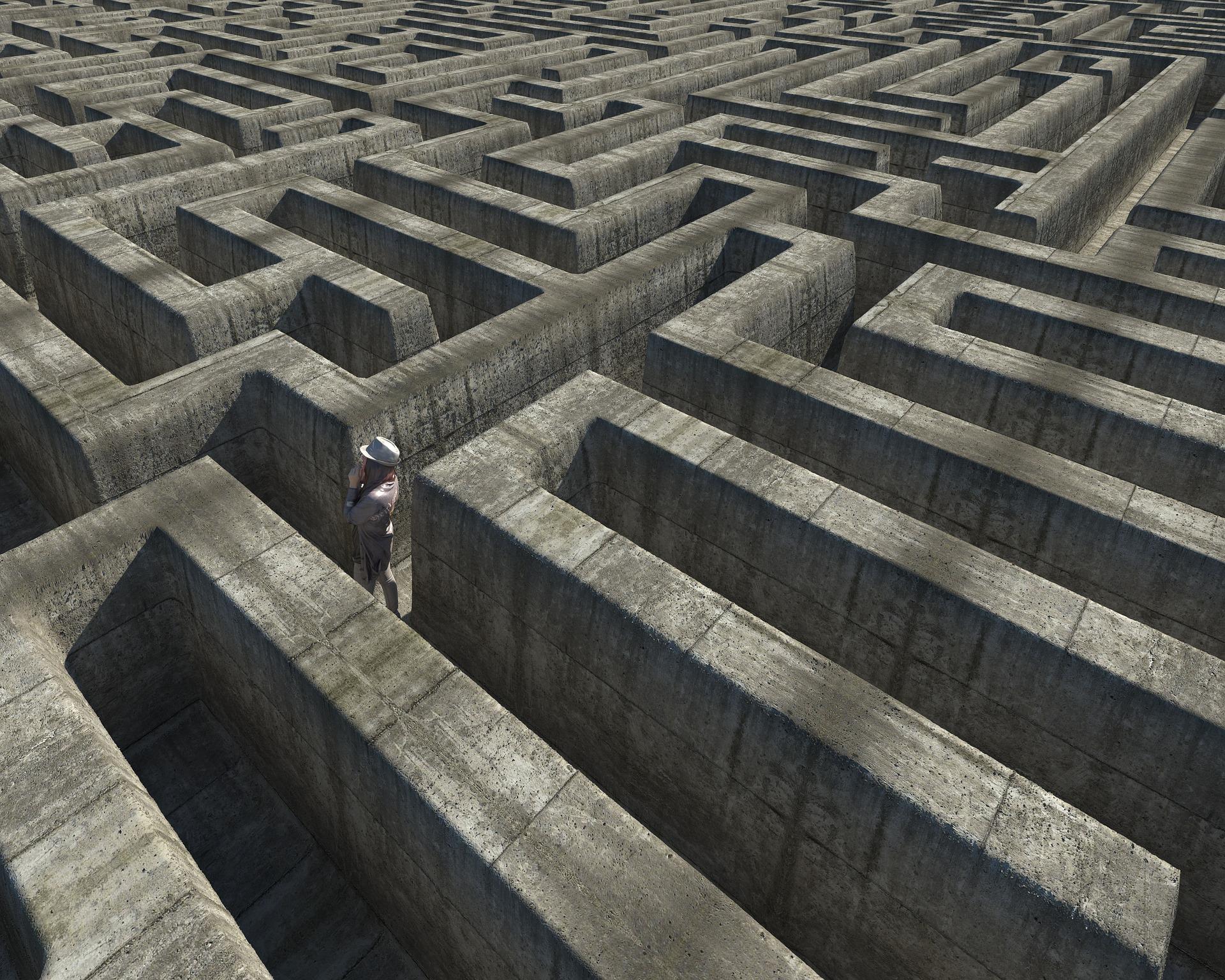 picture taken from above of a person inside a labyrinth, looking towards the left side of the picture, at a wall 