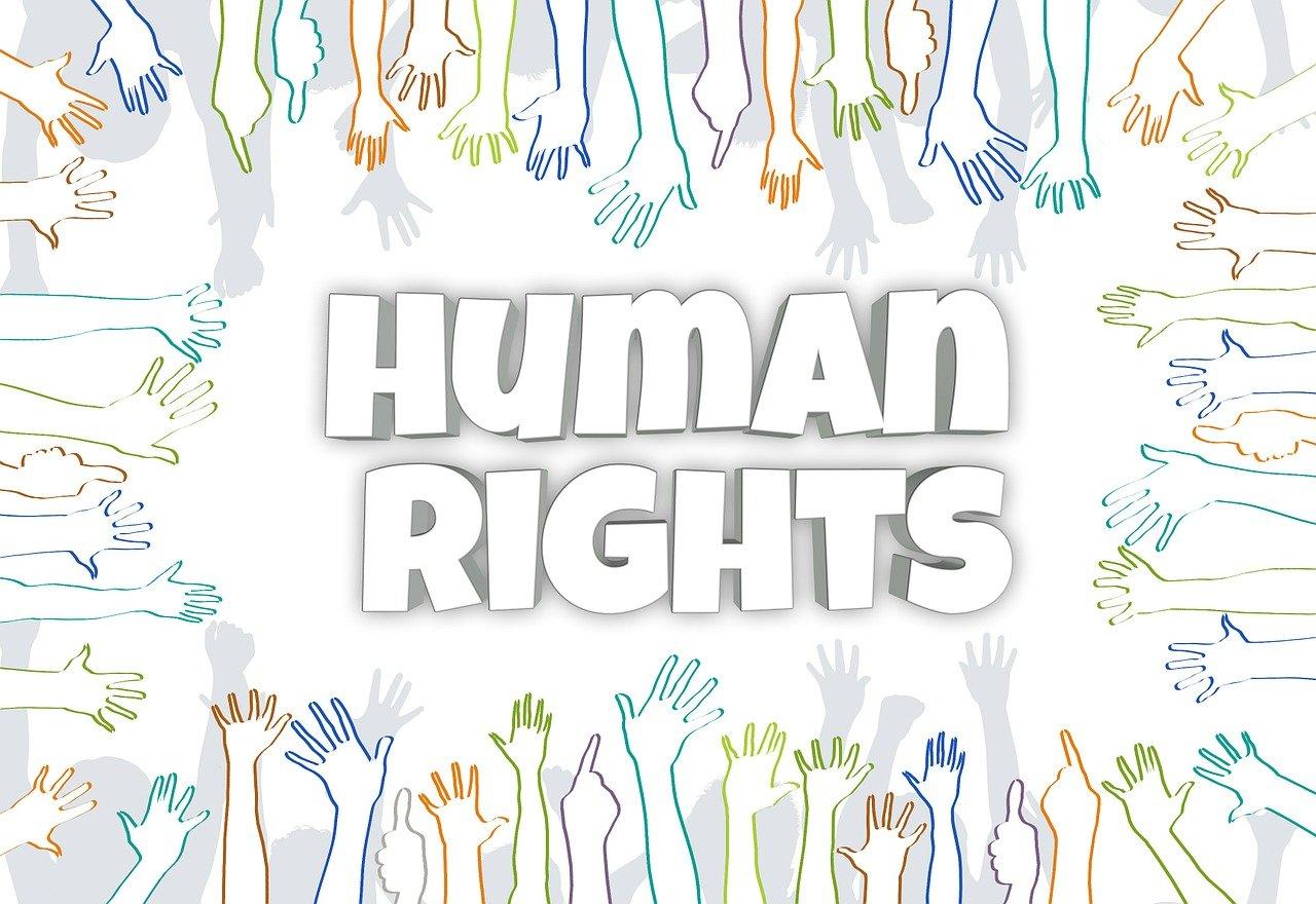 The phrase human rights in bold letters in the center surrounded by drawn cartoon hands reaching out towards it