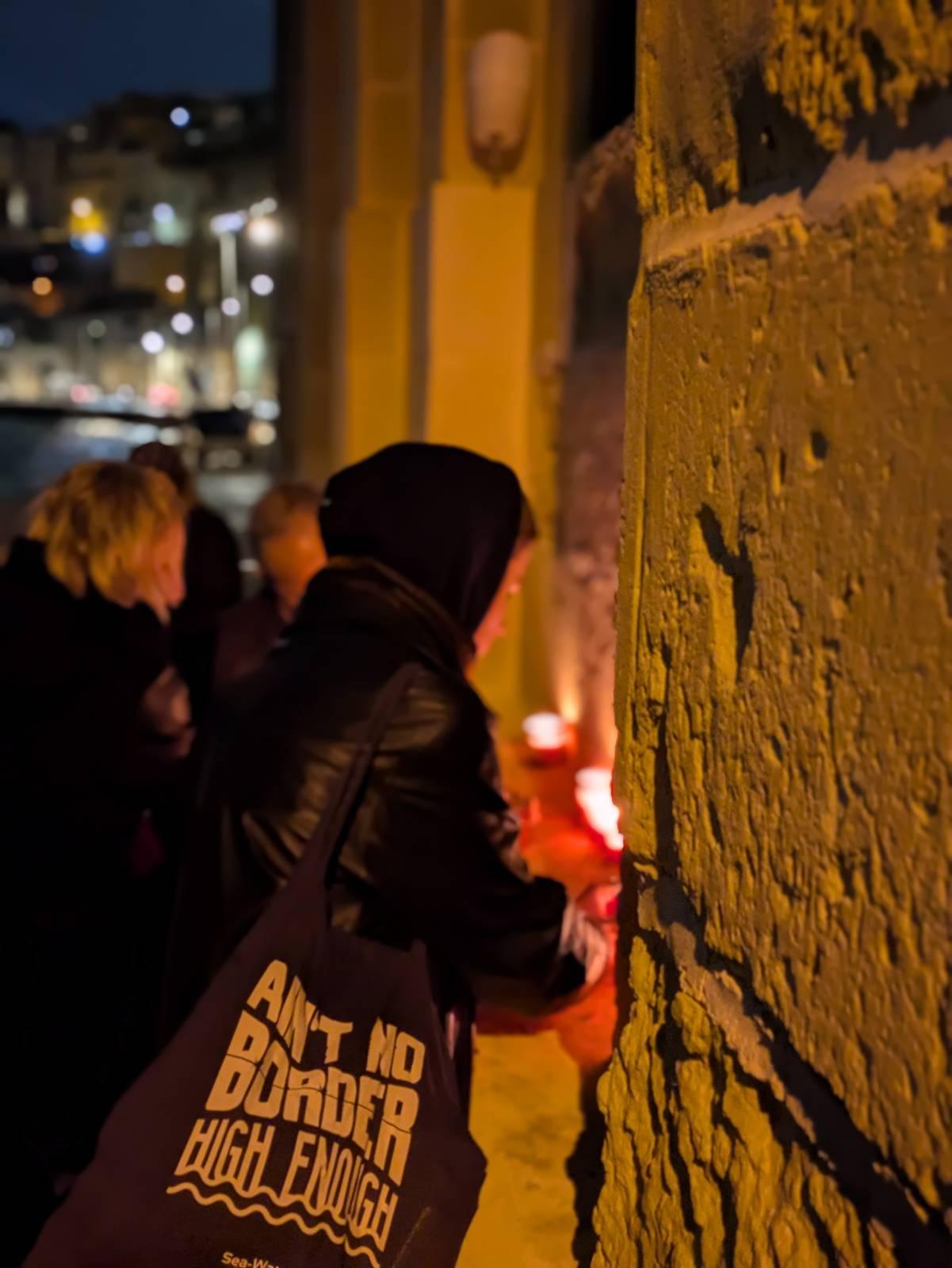An activist lights a candle at the 2025 CommemorAction in Malta.