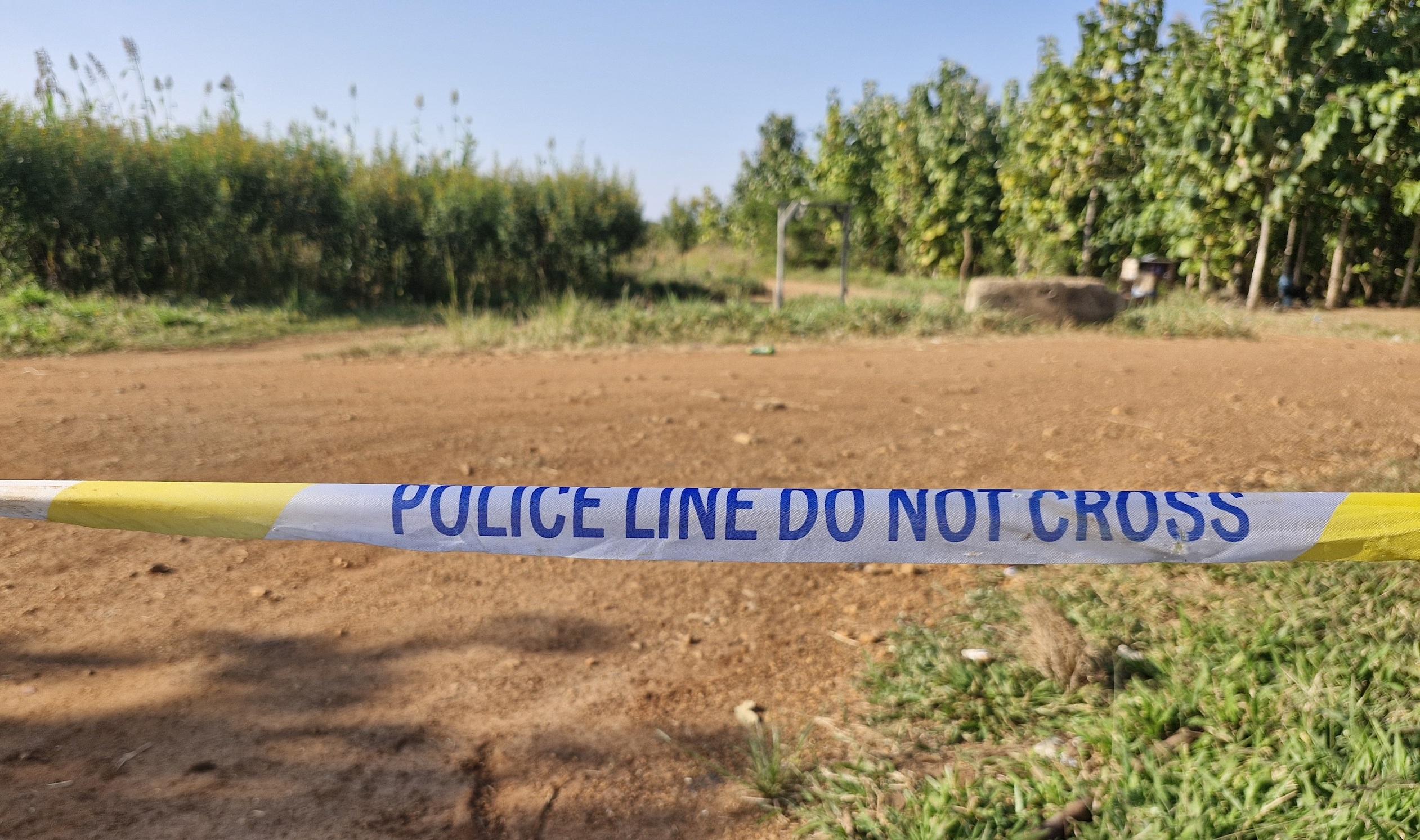 picture of a field with a tape in front of it that says "police do not cross"