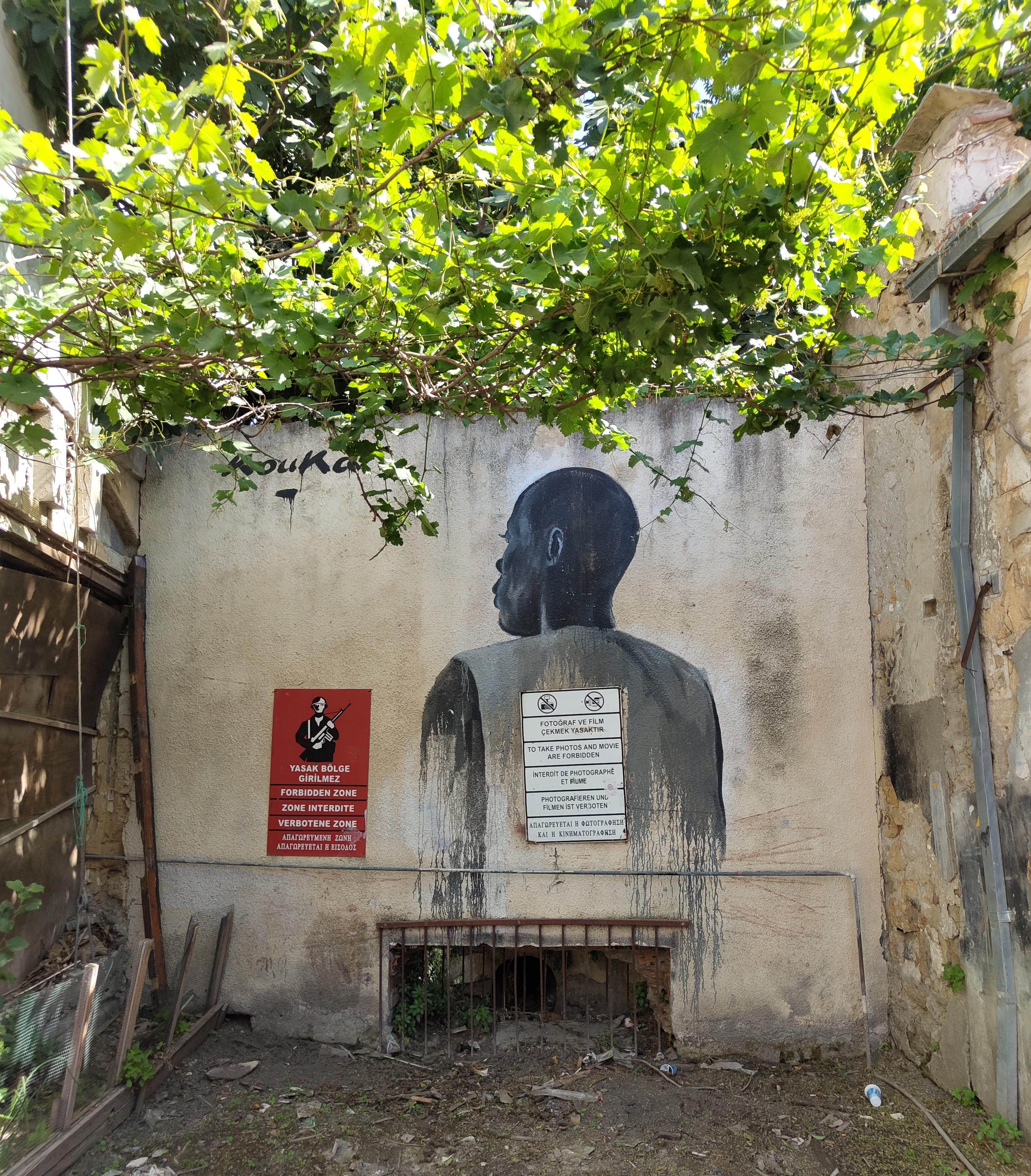 photo of a wall with a mural depicting a man from behind, next to a red sign that says "zone interdite"