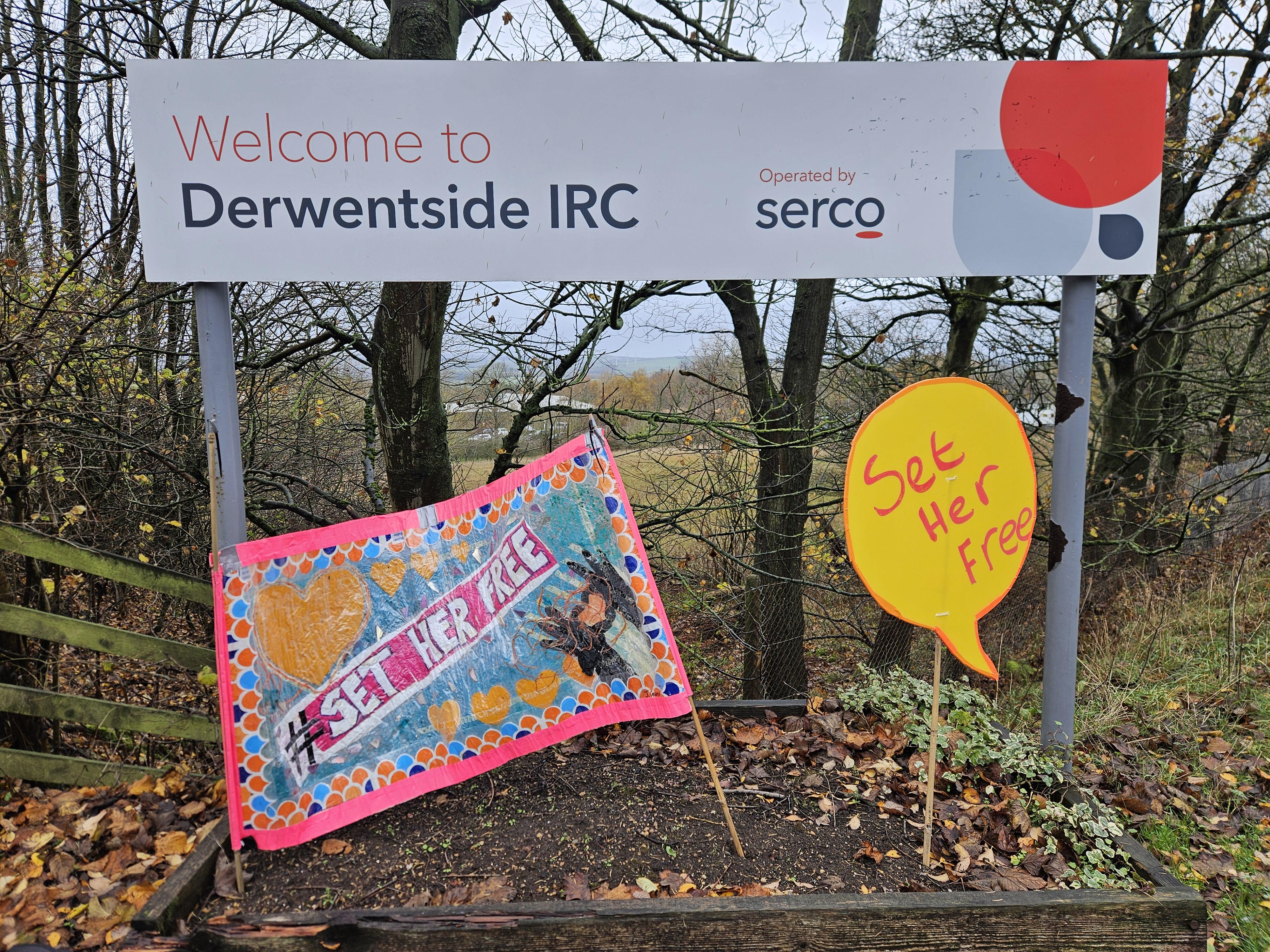A sign reads 'Welcome to Derwentside IRC' with Serco logo. A pink protest banner has been placed below reading '#SetHerFree' with a yellow placard in speech bubble shape also reading 'Set her free' 
