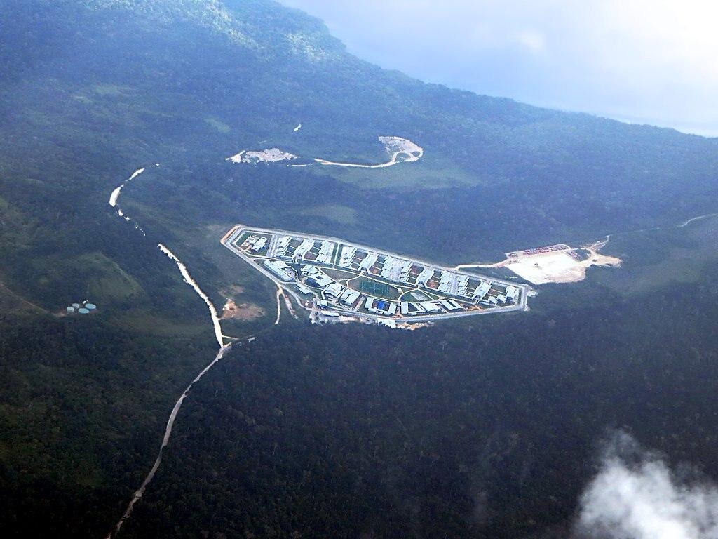 An aerial shot of a detention centre –&nbsp;tightly packed rows of containers arranged in a semi circle shape, surrounded by forest on Christmas Island